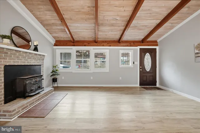 a view of an empty room with wooden floor fireplace and a window