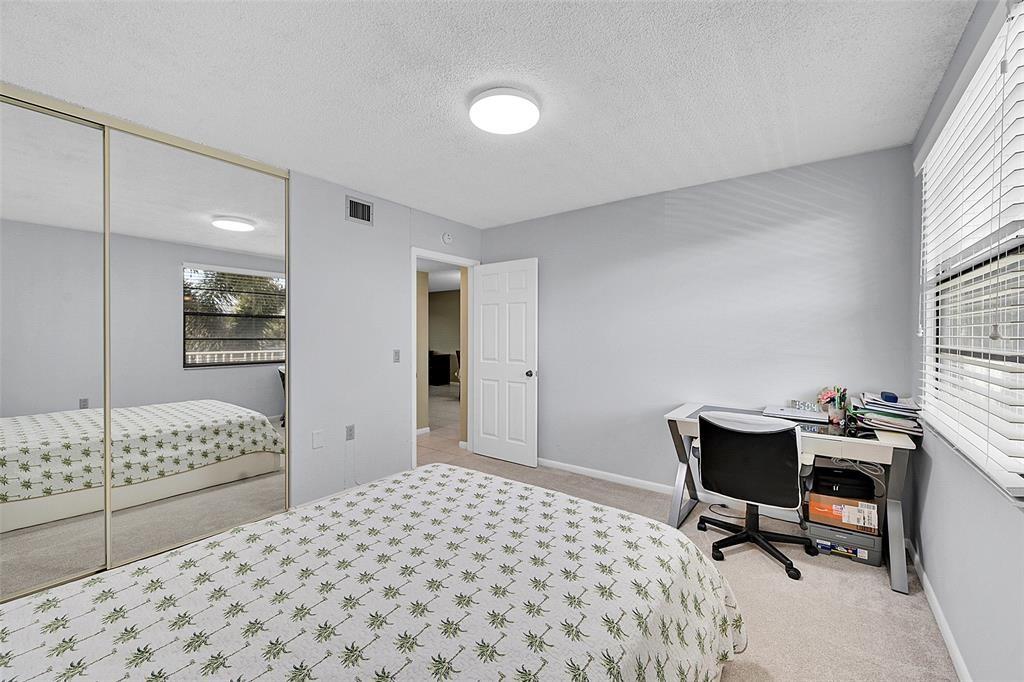 6109 Balboa Circle, Unit 305 Boca Raton, FL 33433 - Photo 15 of 22 a bedroom with a bed a desk and chair