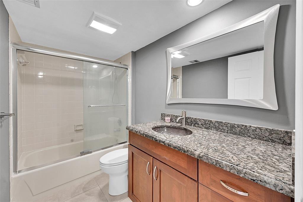 6109 Balboa Circle, Unit 305 Boca Raton, FL 33433 - Photo 16 of 22 a bathroom with a granite countertop sink a toilet and shower