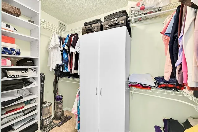 a view of walk in closet with clothes and shoes