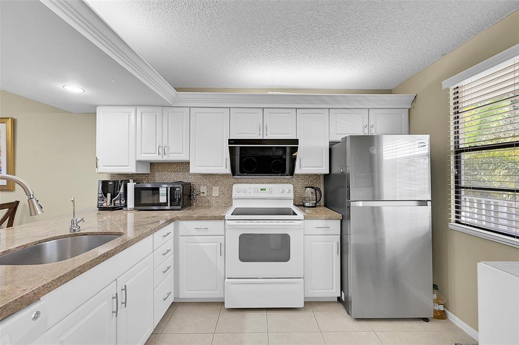 6109 Balboa Circle, Unit 305 Boca Raton, FL 33433 - Photo 5 of 22 a kitchen with white cabinets and white stainless steel appliances and refrigerator