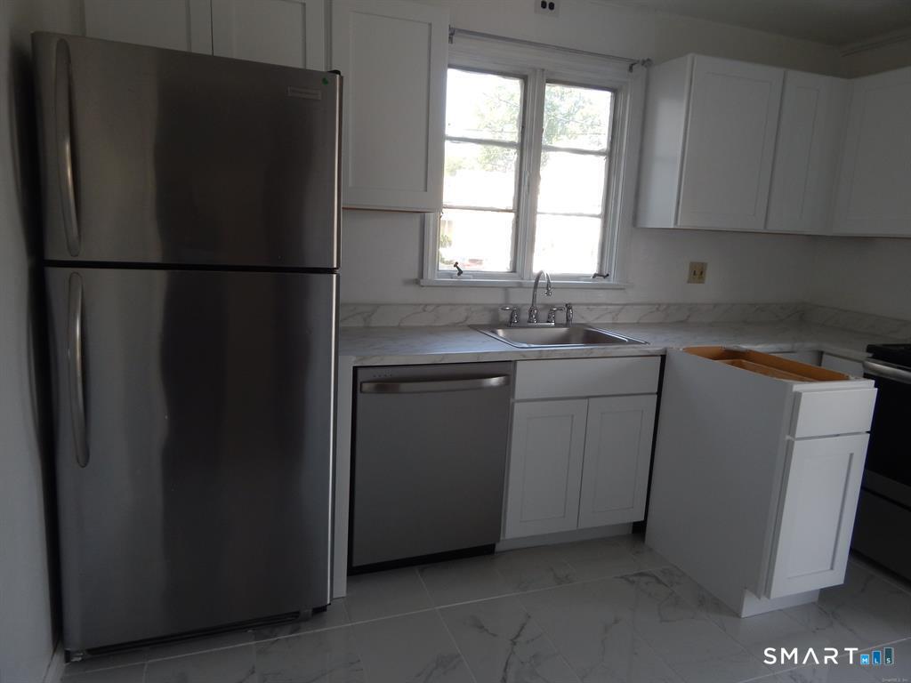 5 Clover Street Ansonia, CT 06401 - Photo 6 of 10 a kitchen with a sink a refrigerator a window and cabinets