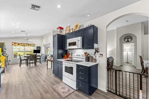 a living room with furniture a flat screen tv and kitchen view