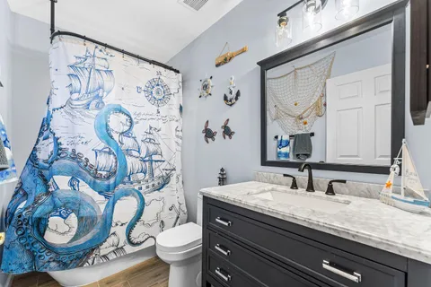 a bathroom with a granite countertop toilet sink and mirror