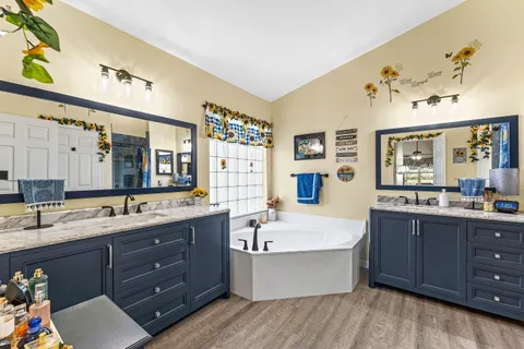 a bathroom with a tub sink double vanity granite and a mirror