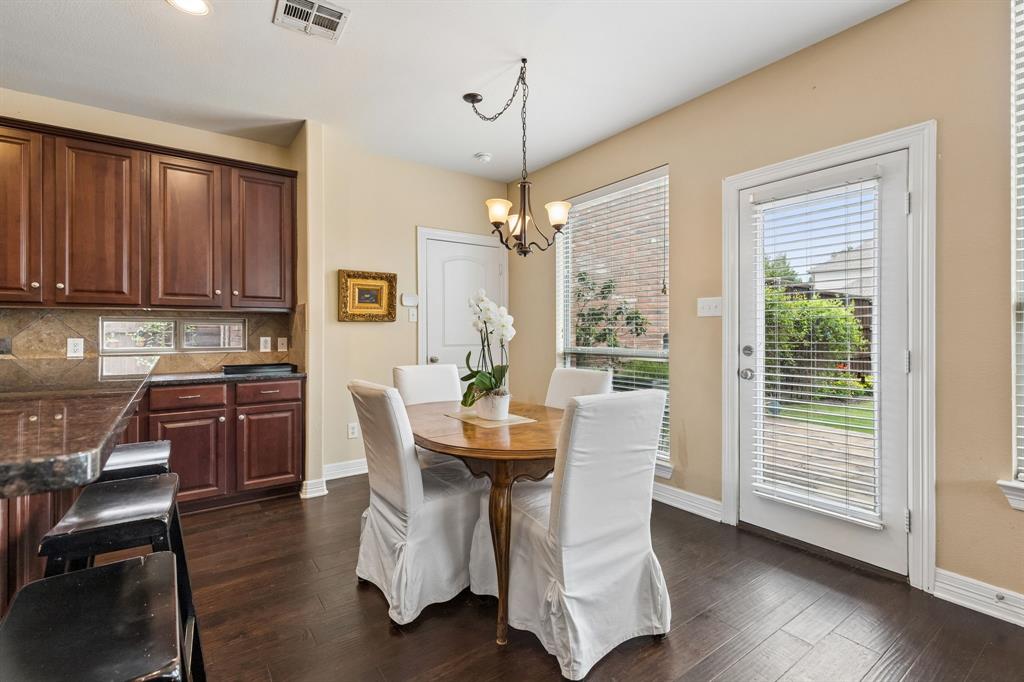 960 Remuda Road Frisco, TX 75033 - Photo 13 of 39 Open-concept dining area featuring dark wood-finish flooring, a contemporary chandelier, two large windows, a glass-paned door, and a built-in breakfast bar with dark countertops