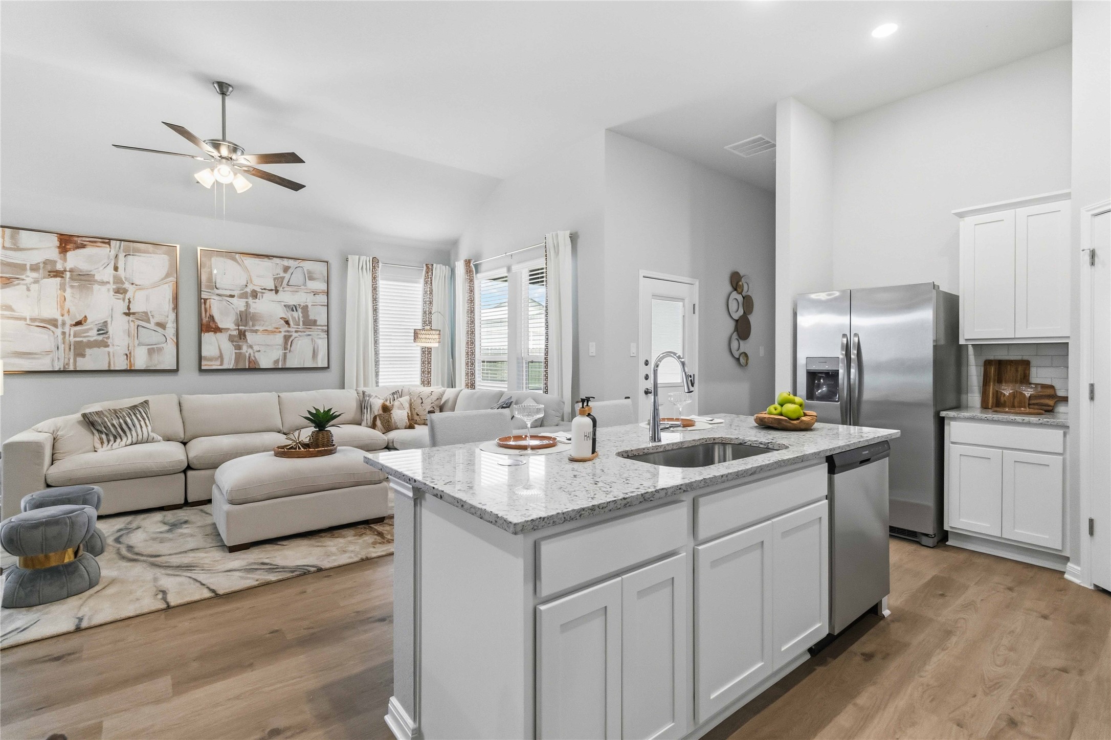 An open-concept living area connects seamlessly to a modern kitchen with recessed lighting and wood floors.