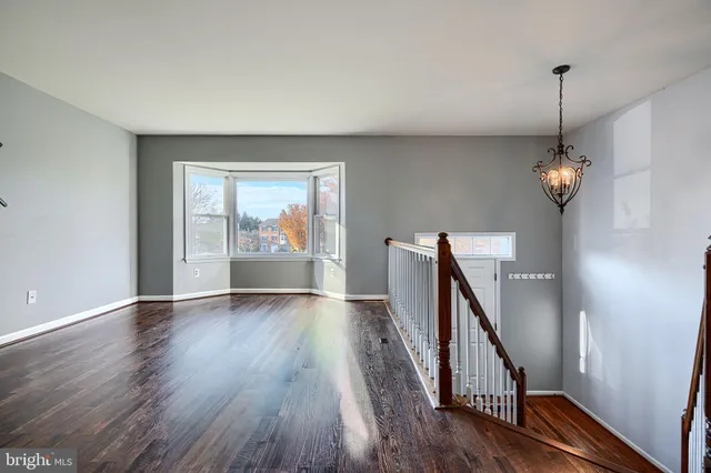 a view of an empty room with wooden floor and window