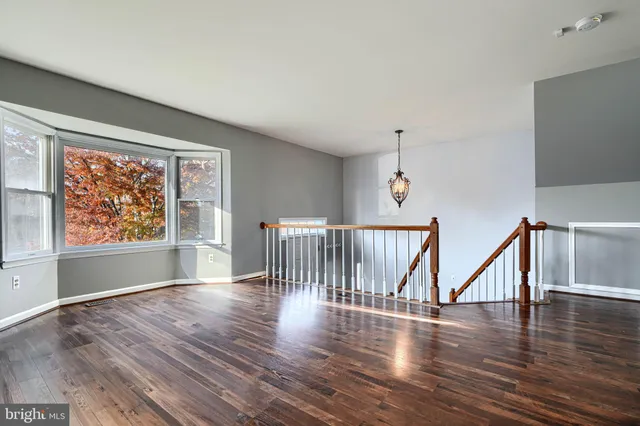 a view of empty room with wooden floor fan and window