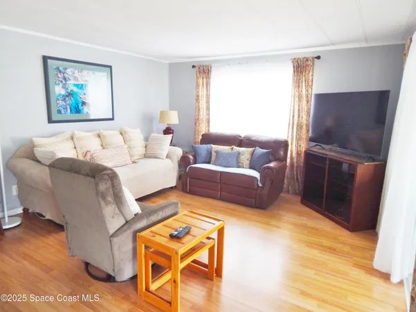 a living room with furniture a refrigerator and a wooden floor