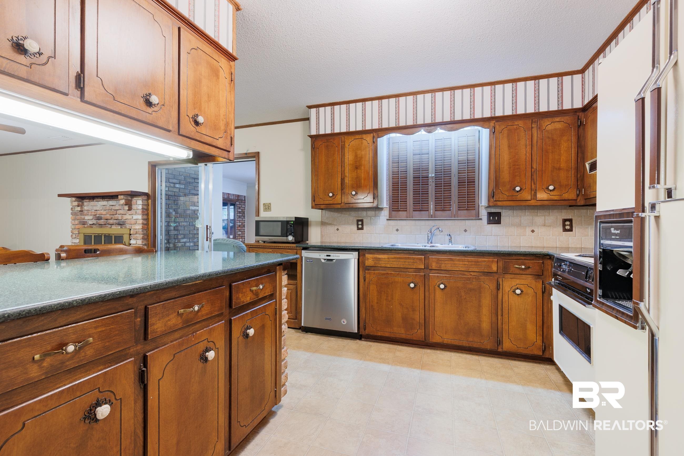1367 Spring Valley Court Mobile, AL 36693 - Photo 6 of 29 Kitchen featuring wood cabinetry, stone-look countertops, and a tiled backsplash