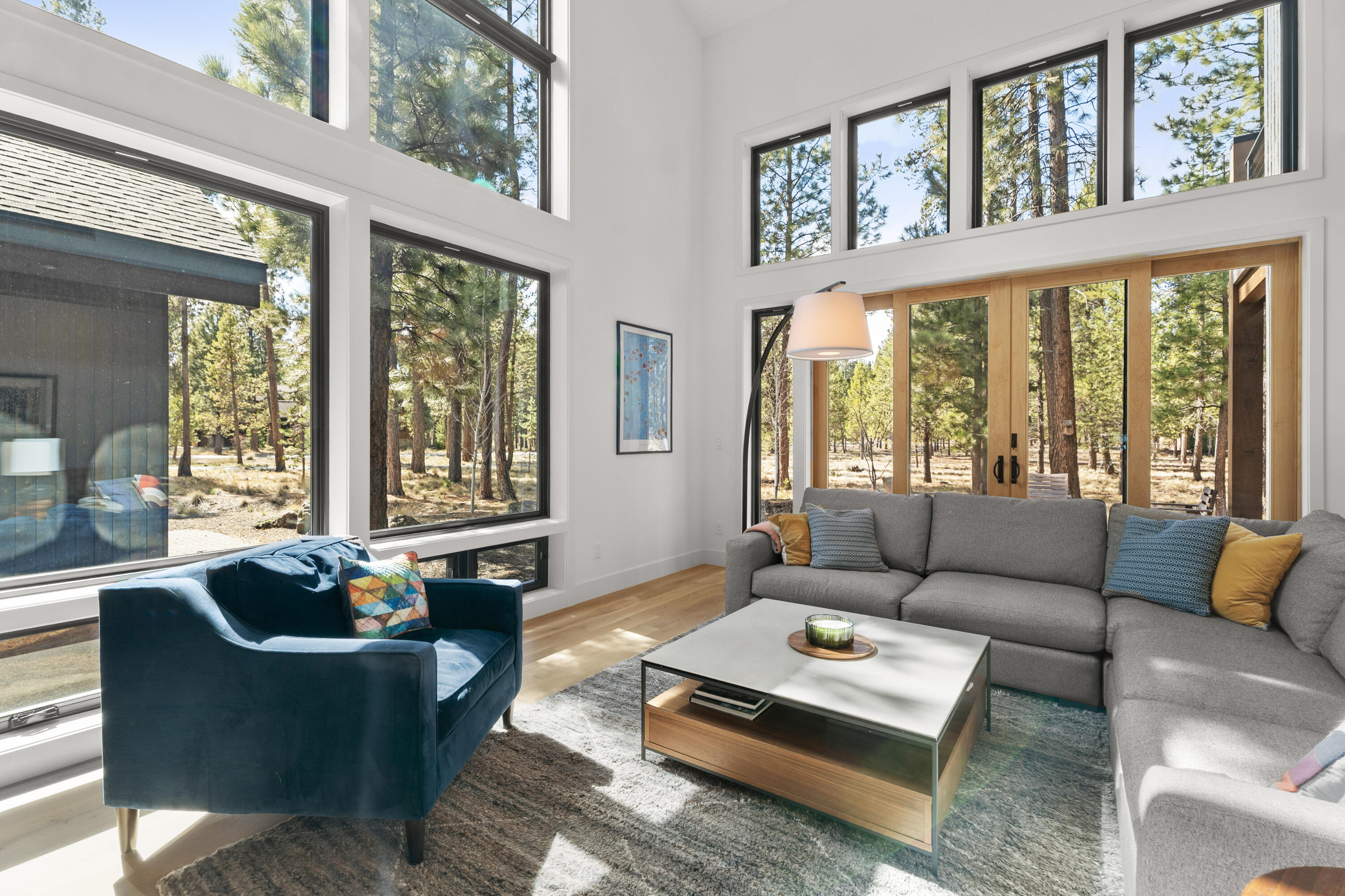 56670 Sunstone Loop, Unit LOT 141 Bend, OR 97707 - Photo 3 of 62 Dramatic, light-filled great room with soaring vaulted ceilings, walls of glass, and a striking floor-to-ceiling poured concrete fireplace surround. Exposed wood accents, clean contemporary lines, and warm natural textures create a true mountain modern centerpiece.