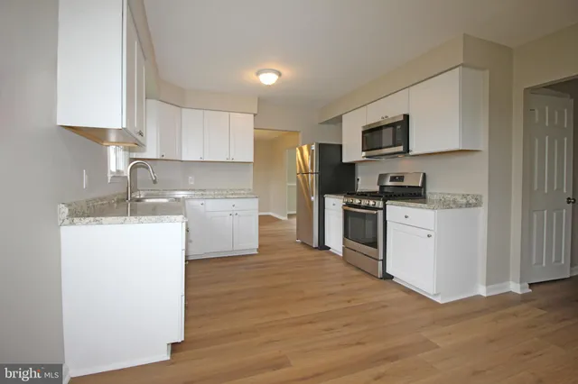 a kitchen with a sink white cabinets and stainless steel appliances