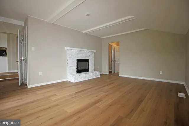 a view of empty room with wooden floor and fireplace