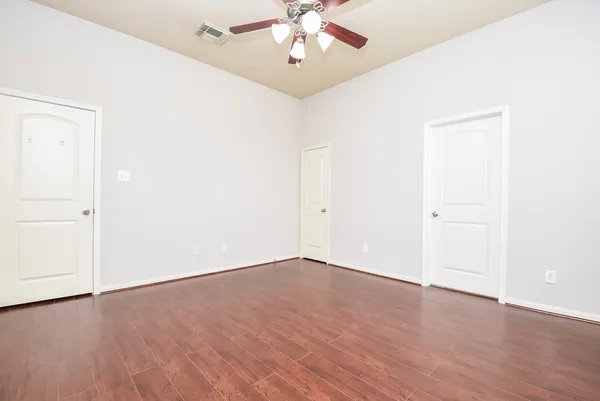 an empty room with wooden floor chandelier fan and closet area