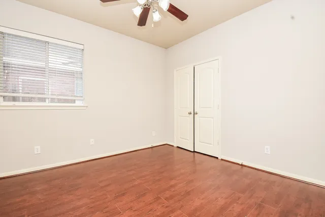 an empty room with a ceiling fan and wooden floor