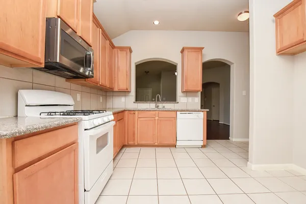 a kitchen with stainless steel appliances granite countertop a stove a sink and a microwave