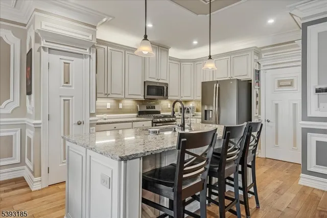 a kitchen with stainless steel appliances granite countertop a refrigerator a stove a microwave oven a sink with a dining table and chairs