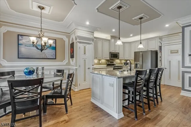 a kitchen with stainless steel appliances kitchen island granite countertop a dining table chairs and a refrigerator