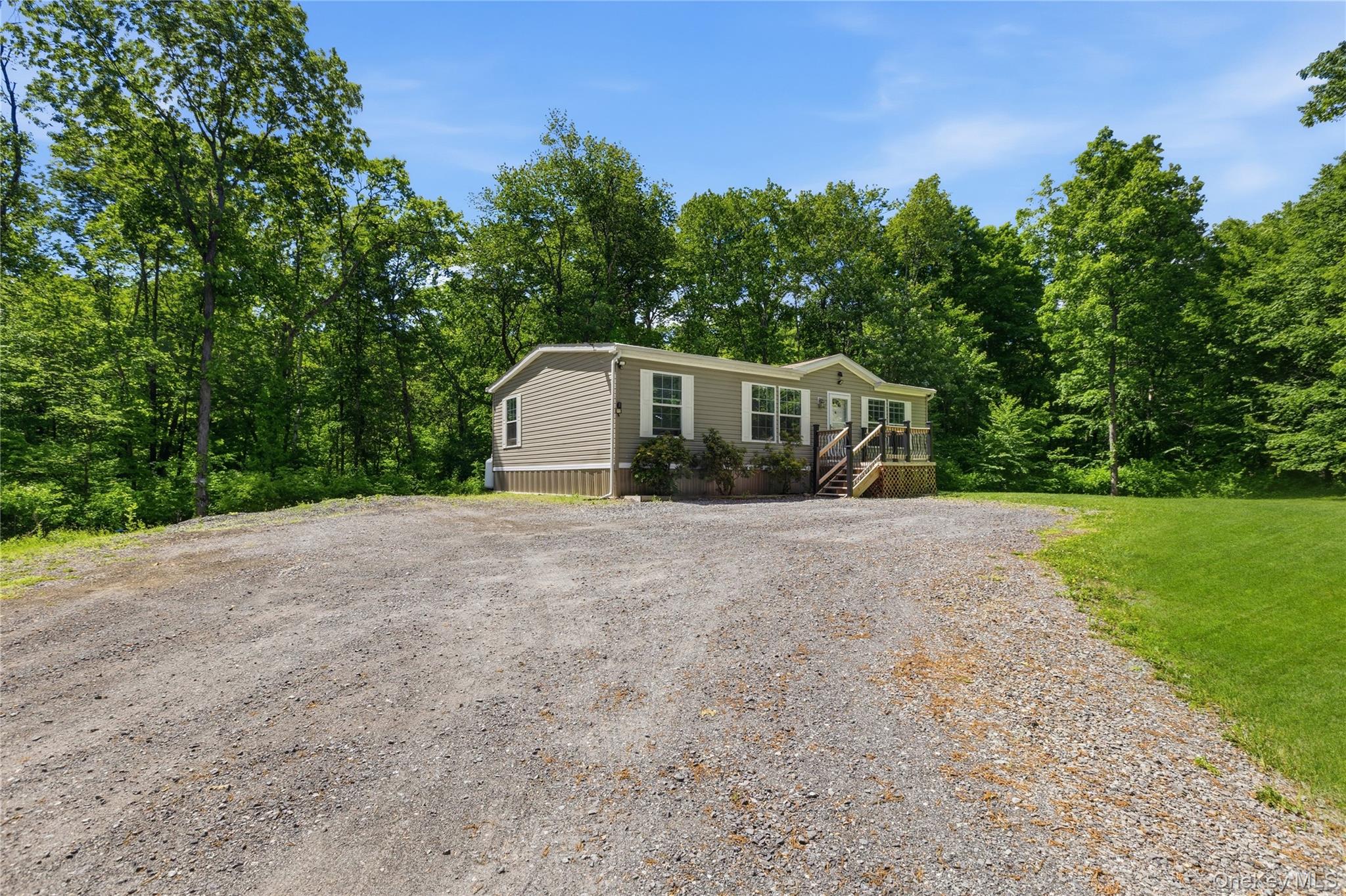 239-241 Fosler Road Highland, NY 12528 - Photo 29 of 42 Single-story residence featuring light gray siding with white trim, a gravel driveway, and a natural tree line backdrop