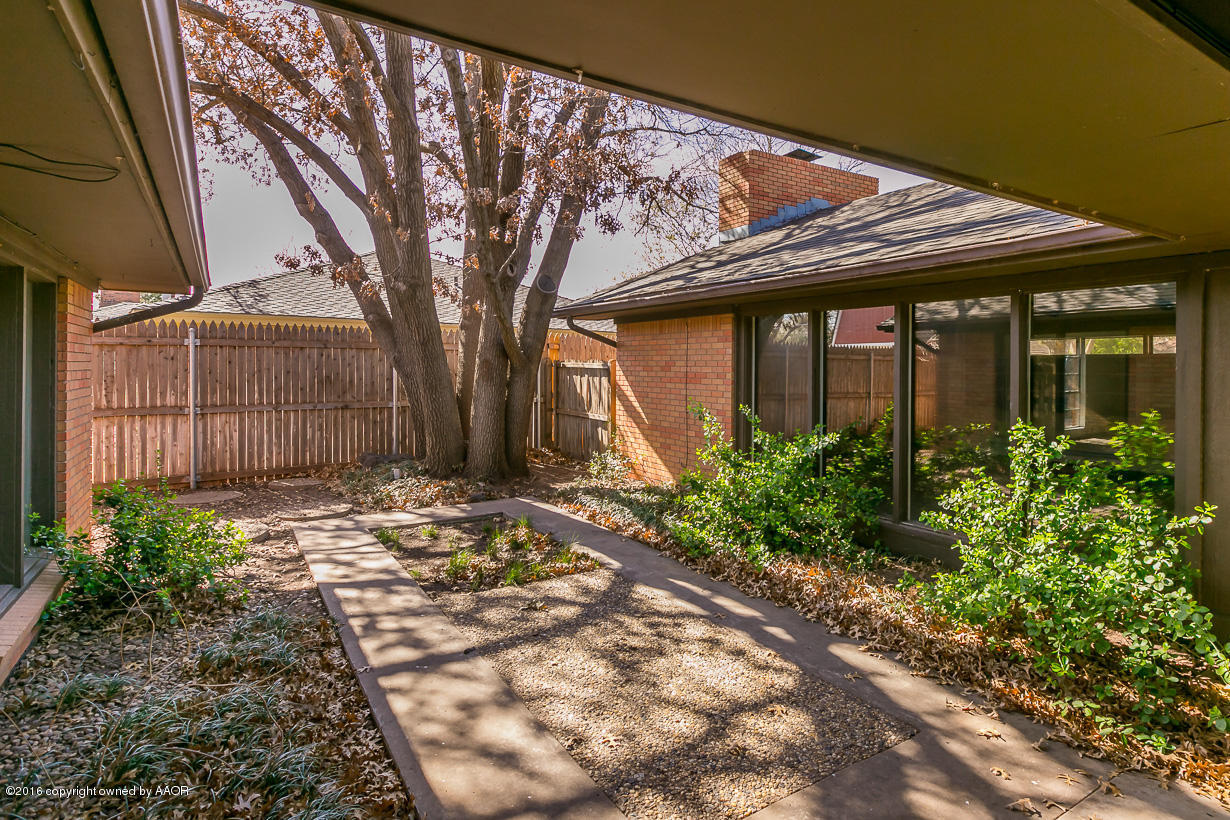 6107 Elmhurst Road Amarillo, TX 79106 - Photo 27 of 32 a view of a house with a small yard plants and large tree