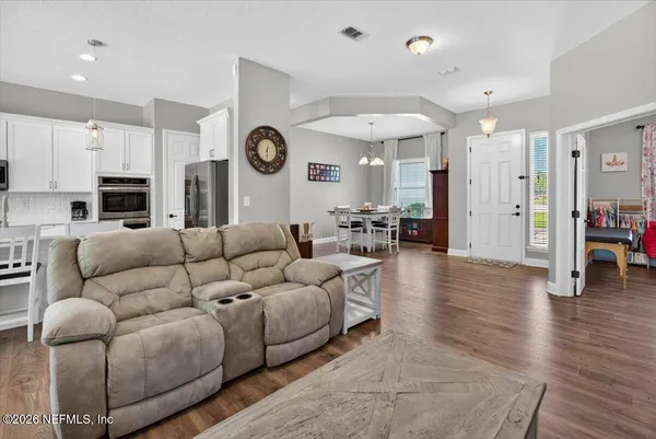 a kitchen with stainless steel appliances a microwave a stove a refrigerator white cabinets and wooden floor