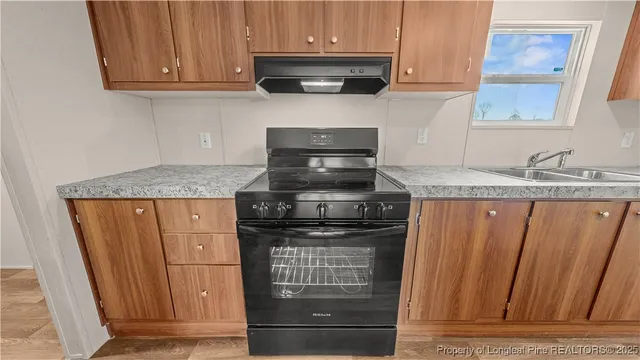 a kitchen with granite countertop wooden cabinets and a stove top oven