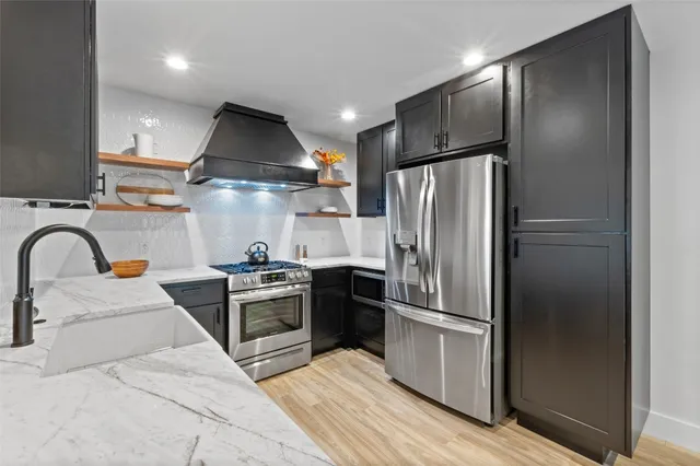 a kitchen with stainless steel appliances granite countertop a refrigerator and a stove top oven