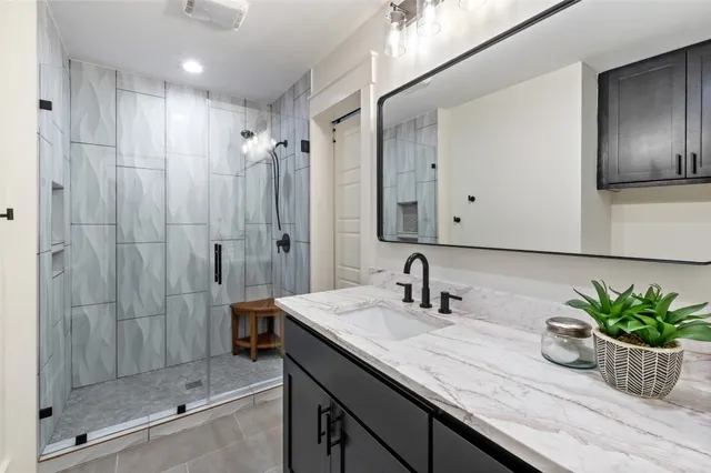 a bathroom with a granite countertop sink a large mirror a shower and a mirror