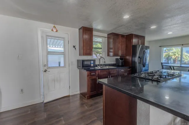 a kitchen with stainless steel appliances granite countertop a sink refrigerator and cabinets