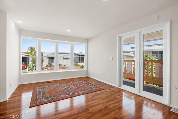a view of an empty room with kitchen and window