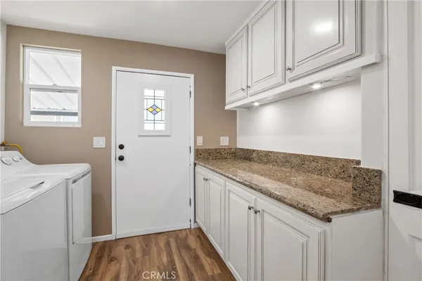 a utility room with granite countertop cabinets washer and dryer