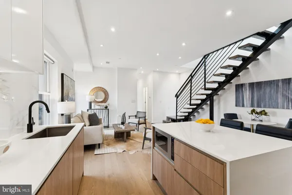 a kitchen with stainless steel appliances a sink dishwasher a stove a dining table and chairs with wooden floor