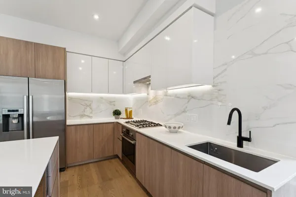 a kitchen with a sink a counter top space stainless steel appliances and cabinets