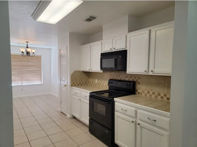 a kitchen with granite countertop white cabinets and appliances