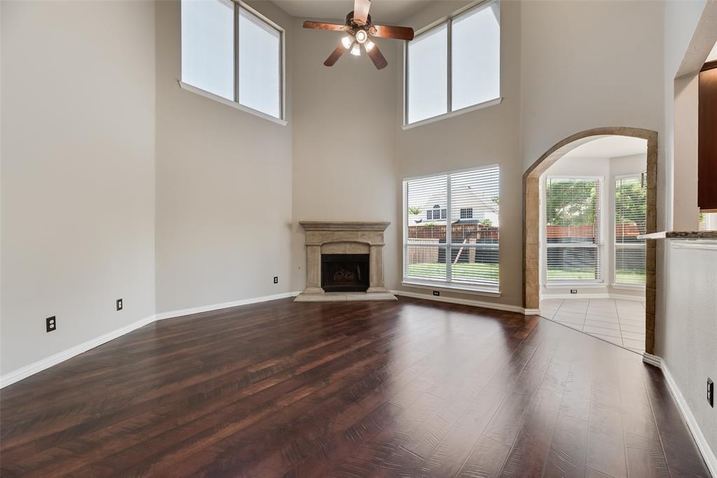 11104 Rogers Road Frisco, TX 75033 - Photo 3 of 40 Unfurnished living room featuring a ceiling fan, dark wood-type flooring, healthy amount of natural light, a high end fireplace, and a high ceiling