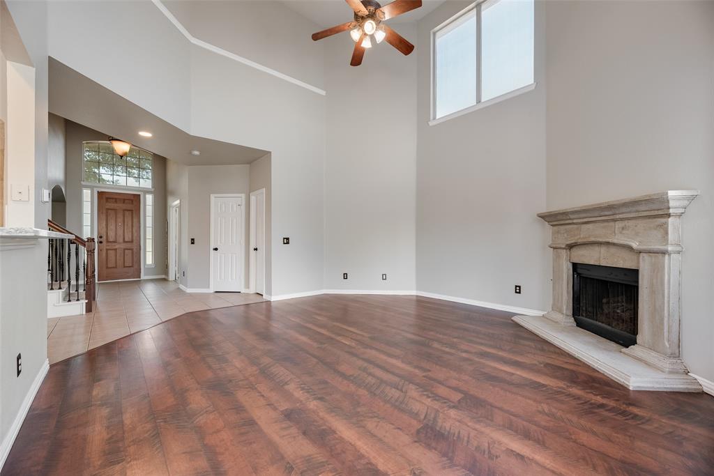 11104 Rogers Road Frisco, TX 75033 - Photo 6 of 40 Unfurnished living room with plenty of natural light, a premium fireplace, dark wood finished floors, a high ceiling, and a ceiling fan