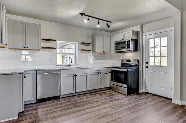 a kitchen with stainless steel appliances granite countertop a stove a sink and a microwave