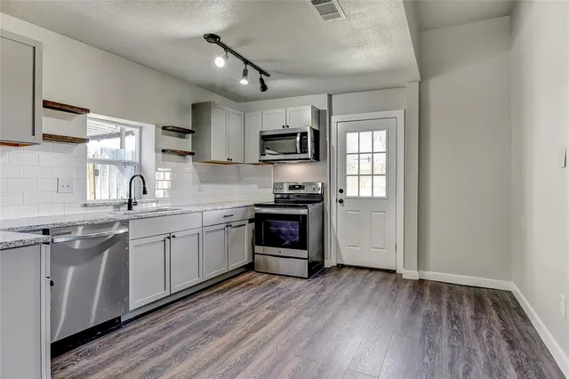 a kitchen with granite countertop a refrigerator and a stove top oven