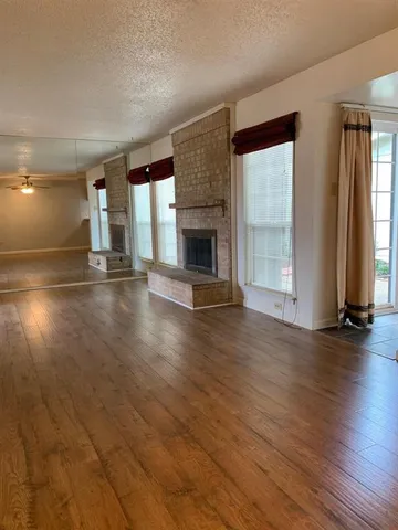 an empty room with floor to ceiling window and wooden floor