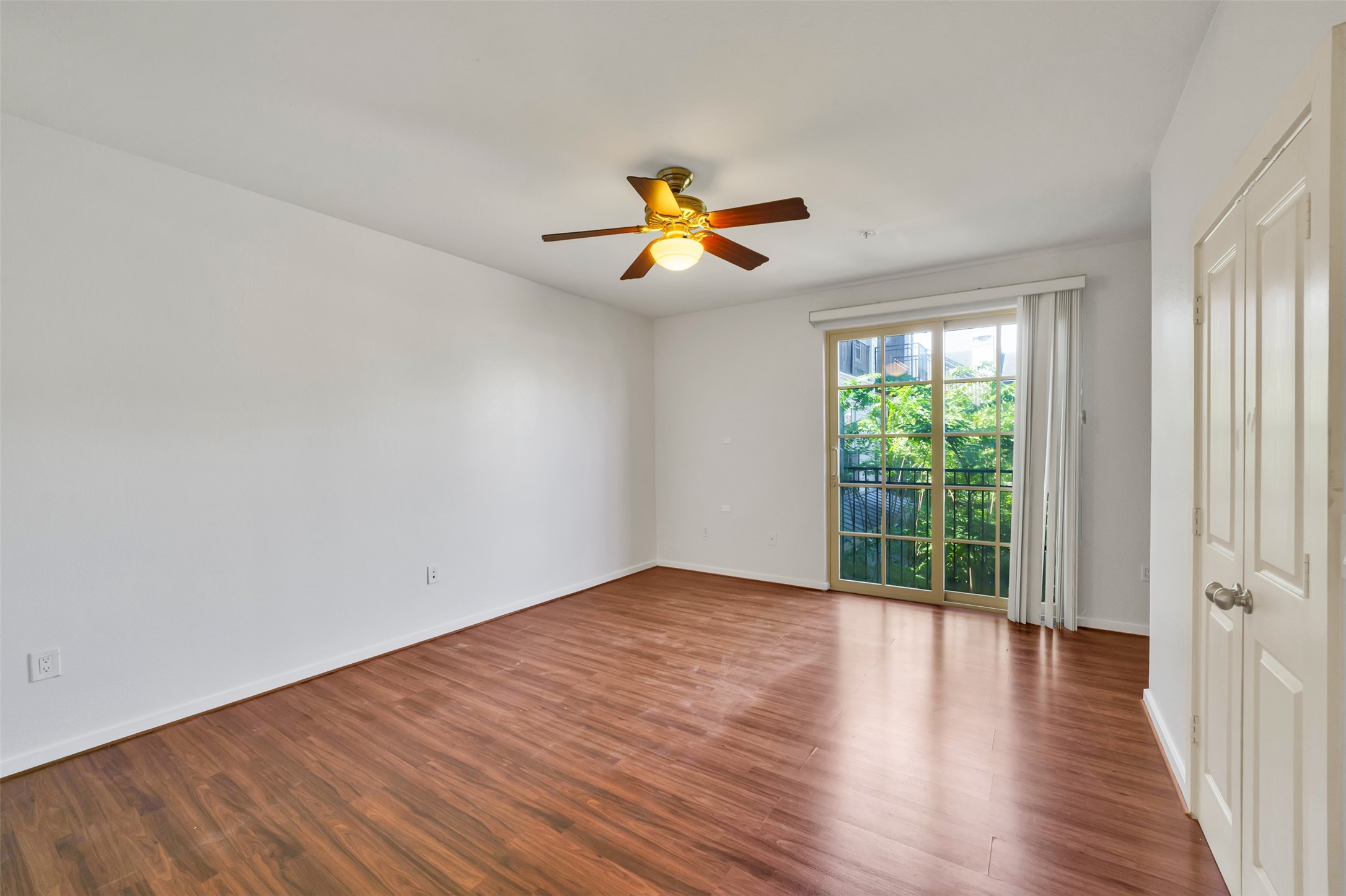 2216 Chenevert Street, Unit 6 Houston, TX 77003 - Photo 11 of 29 Primary Bedroom (upstairs): Attractive primary suite built for tenant appeal, showcasing wood flooring, a Juliet balcony with Downtown and community courtyard views, a built-in desk for remote work, two closets, and a private ensuite bath...features that support strong, stable rental performance.