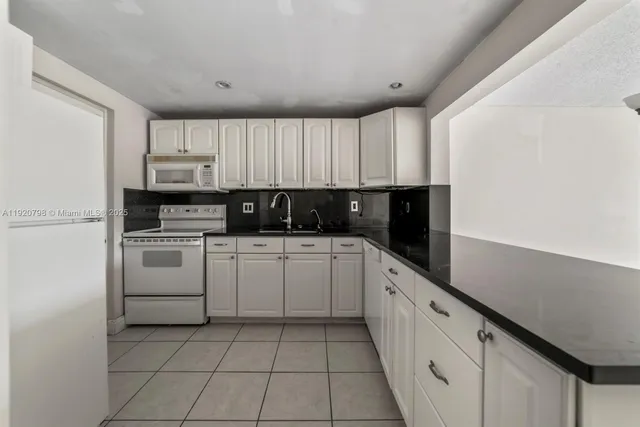 a kitchen with white cabinets and white appliances