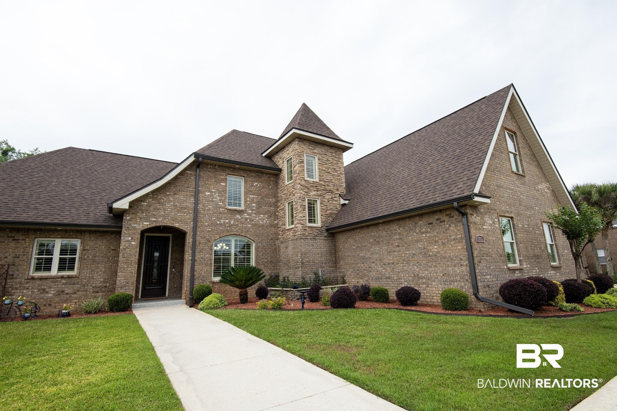 9357 Lakeview Drive Foley, AL 36535 - Photo 9 of 68 Brick exterior residence with a prominent turret, dark shingle roofing, and multiple gables