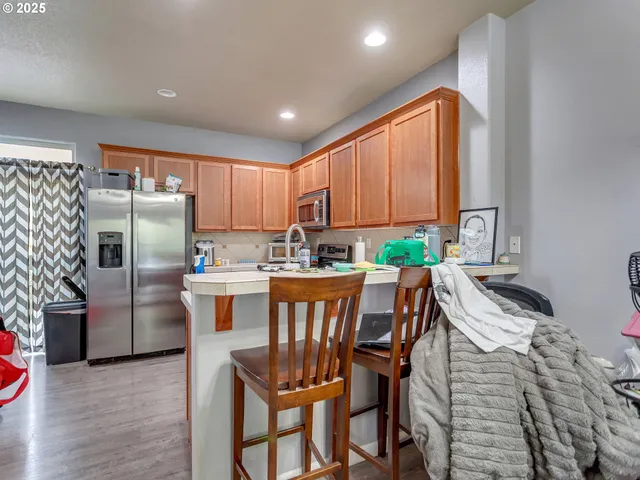 a kitchen with stainless steel appliances a dining table chairs refrigerator and sink