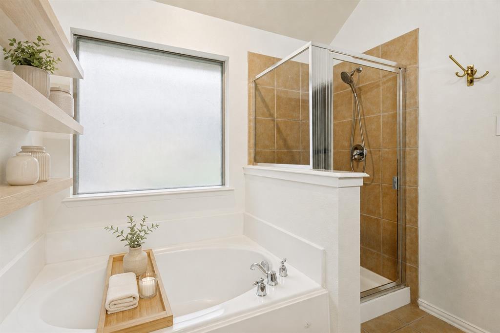 1316 Mountain Air Trail Fort Worth, TX 76131 - Photo 15 of 23 Built-in bathtub with deck-mounted fixtures, separate glass-enclosed shower with tile surround, and floating wood shelves