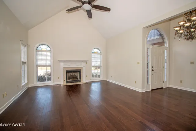 an empty room with wooden floor fireplace and windows