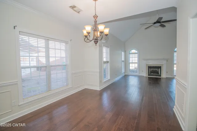 a view of a livingroom with wooden floor a ceiling fan and windows