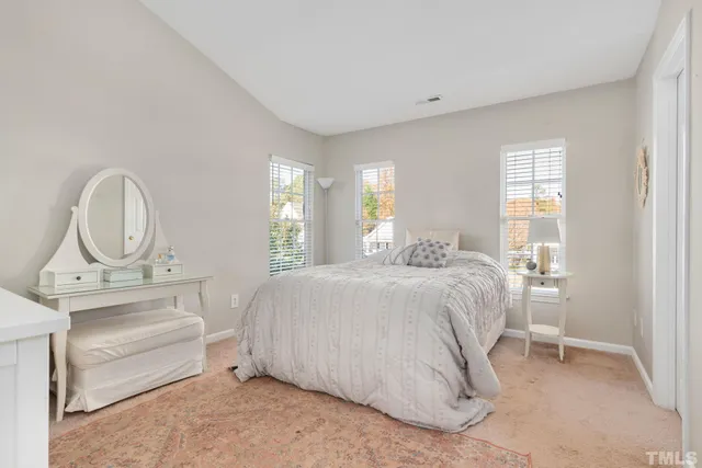 a spacious bedroom with a bed a mirror and windows