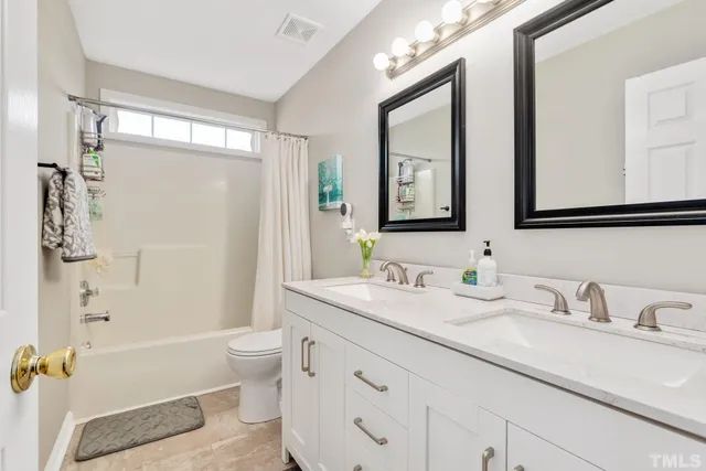 a bathroom with a double vanity sink toilet mirror and bathtub