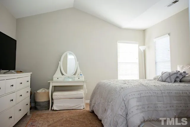 a bedroom with a bed and a flat tv screen on the dresser